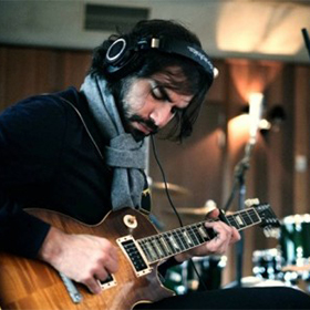 A man playing a guitar in the studio