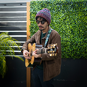 a man wearing a beanie playing guitar