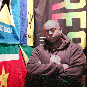 A man standing in a room against a bunch of flags