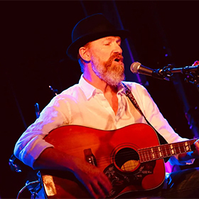 a man with a beard playing guitar and singing