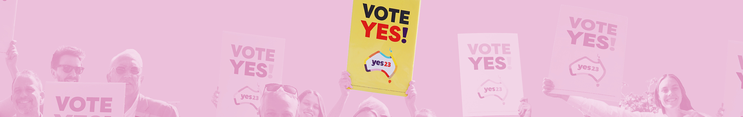 A pink tinted regtangualr banner showing a group of people's heads holding Yes banners. A bright yellow banner in the centre reads Yes 23 in red letters.