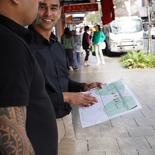 Two people smiling, one holds printed plans of streetscape designs