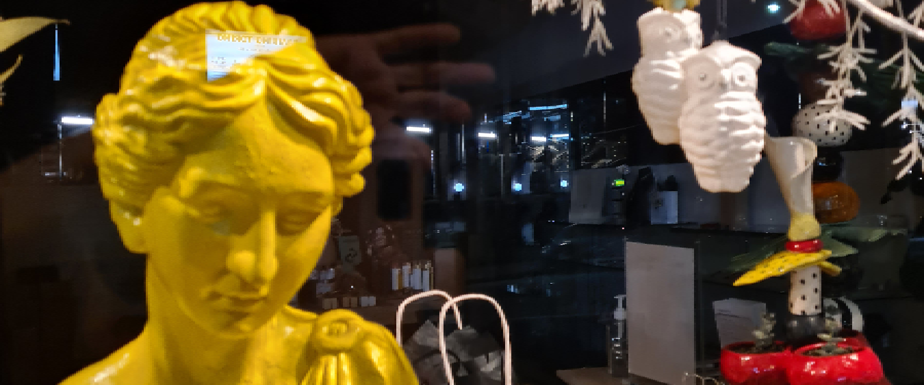 Photo of Connie Dimas store with yellow sculpture of a head and shoulders of a female figure it has a 1920s vibe, in the background you can see jewellery and foliage