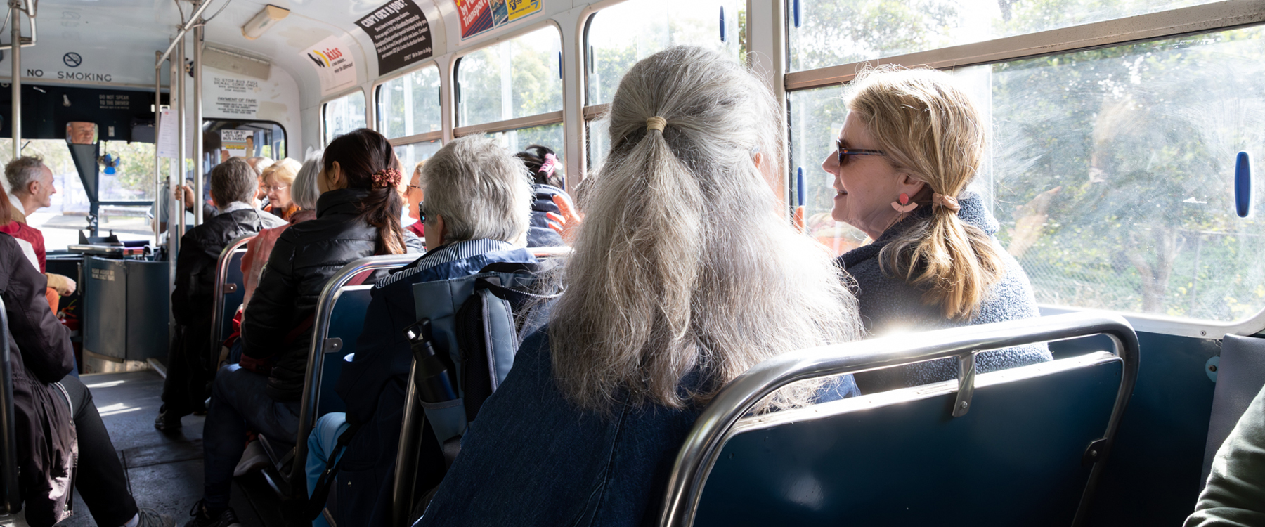 Photo of people inside a bus, they are visible from behind