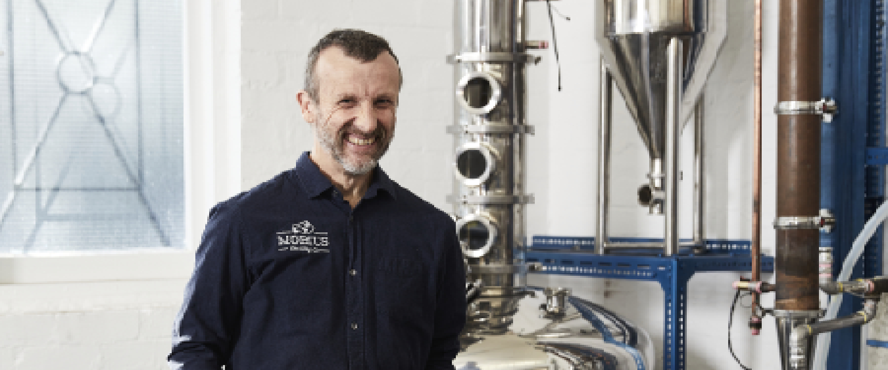 Photo of staff from Mobius Distilllery, they stand smiling and in the background you can see distilling equipment and machinery 