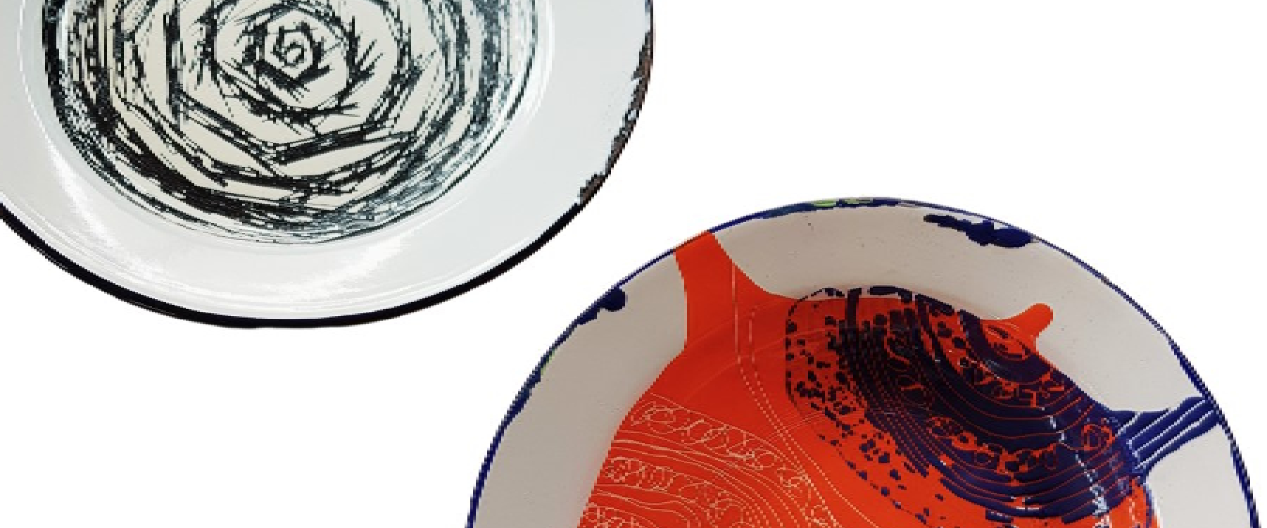 Cropped photo of two enamel plates both have been re-created with designs in the centre of the plate one is a navy spiral with scratchy lined edges the other is red and navy blue with a shell like motif