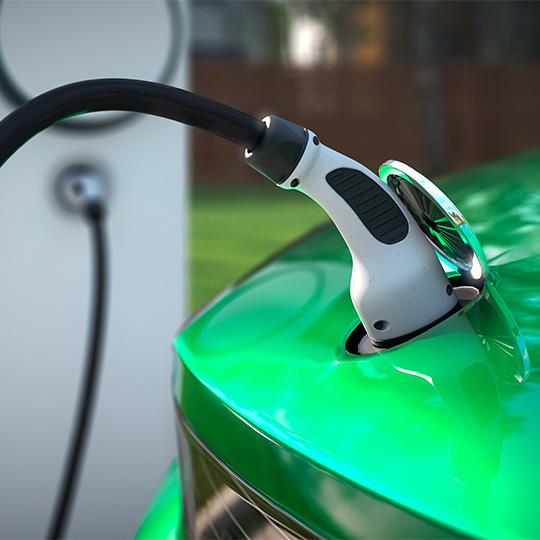 A green electric vehicle being charged at a public charging point.