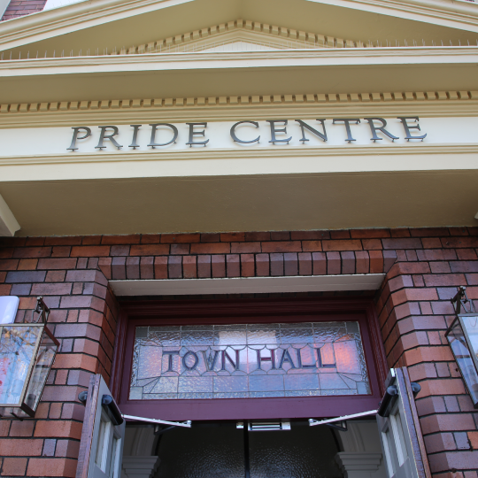 Close up image of Council Town Hall with ornate metal lettering that reads 'Pride Centre. Underneath it reads: Town Hall