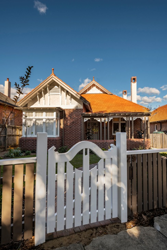 an image of a house with a white fence at the front