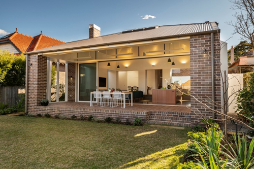 an image of the back of a house with a open space are through the house and a white table outside