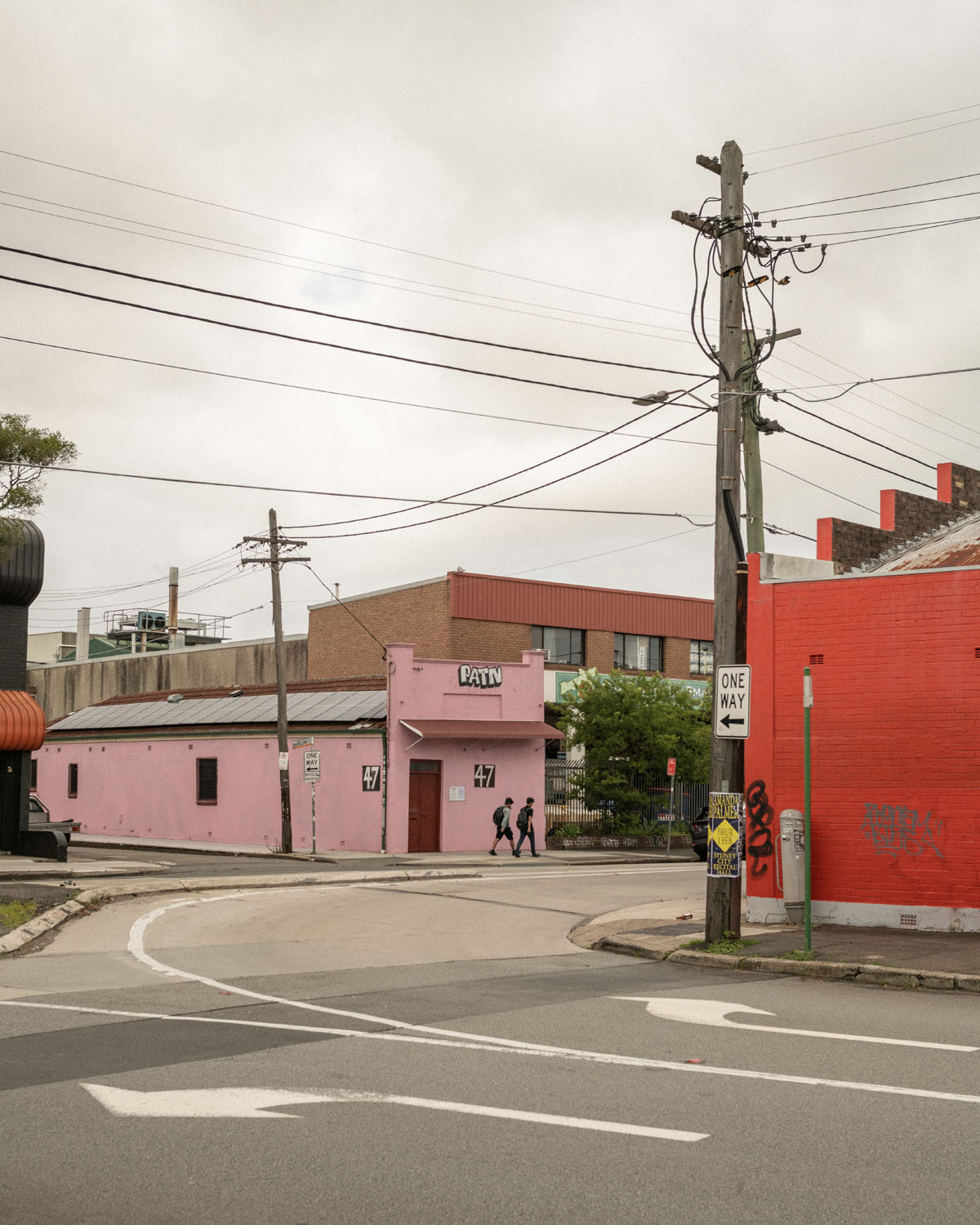 Buildings in an industrial area, one painted a bright red and another bright pink. A system of streets runs between them.