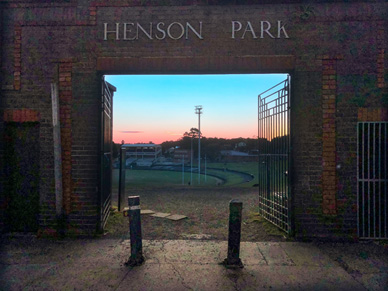 A brick gate with the text Henson Park on its top arch opens up to a sporting ground.